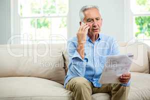 Old man talking on phone in living room at home