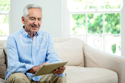 Smiling senior man using digital tablet at home