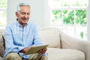 Smiling senior man using digital tablet at home