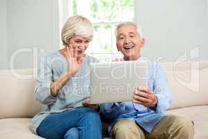 Happy senior couple looking into digital tablet at home