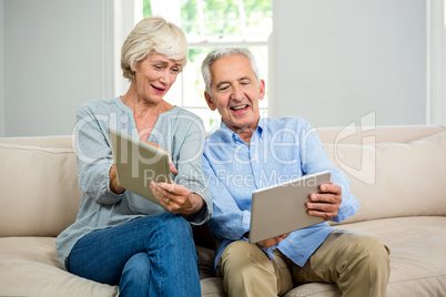 Smiling senior couple using digital tablet at home