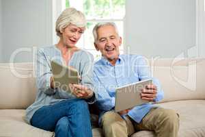 Smiling senior couple using digital tablet at home