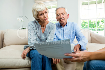 Cropped image of consultant showing report to aged couple