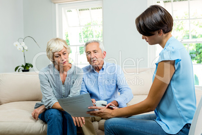 Female consultant showing report to old couple at home