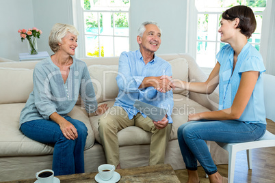 Smiling senior couple with female consultant at home