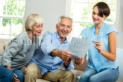 Smiling female consultant showing report to senior couple