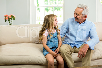 Happy grandfather and girl sitting on sofa