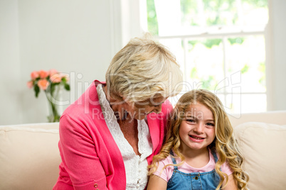 Smiling granny and girl sitting on sofa