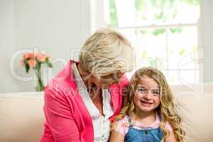 Smiling granny and girl sitting on sofa