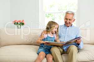 Smiling girl and granddad with picture book