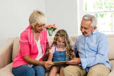 Happy grandparents and girl using digital tablet