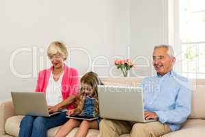 Happy grandparents and girl using technology
