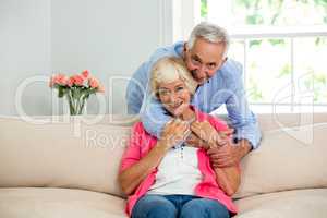 Cheerful senior couple hugging at sofa