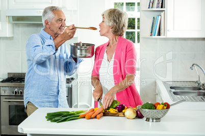 Smiling senior man feeding food to woman