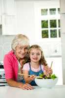 Portrait of happy granny and girl preparing vegetables