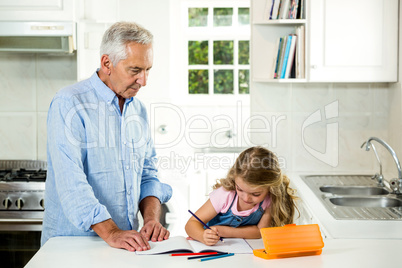 Girl studying at table with granddad