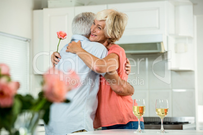 Smiling senior woman hugging man with rose