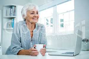 Thoughtful senior woman with coffee mug