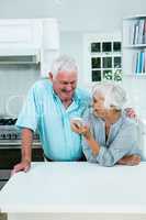 Smiling senior woman showing phone to man