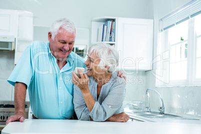 Happy senior woman showing phone to man