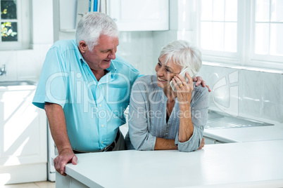Smiling woman talking on phone while standing with man