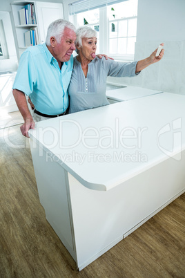 Playful senior couple making faces while taking selfie