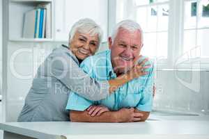 Happy senior woman embracing man at home