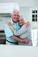 Cheerful senior couple hugging in kitchen