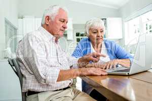 Serious retired man pointing at laptop