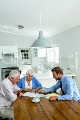 Senior couple with agent while sitting at table