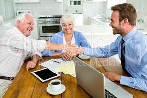 Happy senior man handshaking with agent