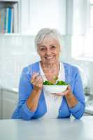 Senior woman eating salad in kitchen