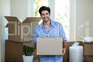 Young man standing with unpacking carton boxes in house