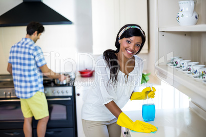 Woman cleaning the kitchen and man cooking food in background