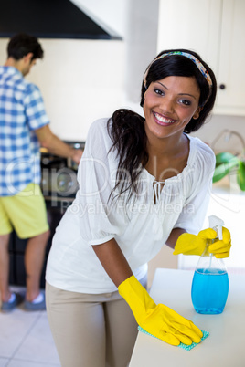 Woman cleaning the kitchen and man cooking food in background