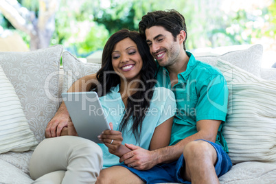 Young couple sitting on sofa and using digital tablet