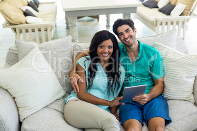 Portrait of young couple sitting on sofa and using digital table