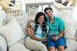 Portrait of young couple sitting on sofa and using digital table