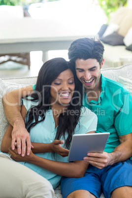 Young couple sitting on sofa and using digital tablet