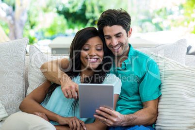 Young couple sitting on sofa and using digital tablet