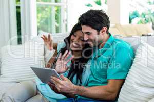 Couple waving hands while using digital tablet for video chat