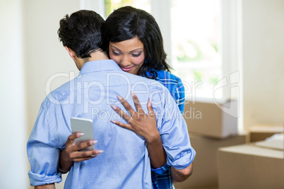 Woman checking her mobile phone while embracing a man