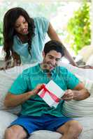 Woman watching a man while unwrapping a gift