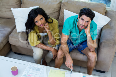 Portrait of worried young couple with bills