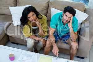 Portrait of worried young couple with bills