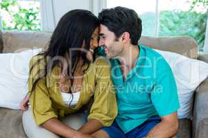 Young couple sitting on sofa and embracing face to face