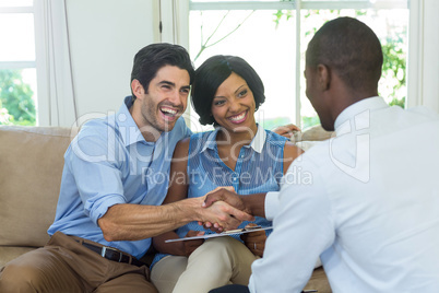 Happy couple shaking hands with real estate agent