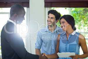 Happy couple shaking hands with real estate agent