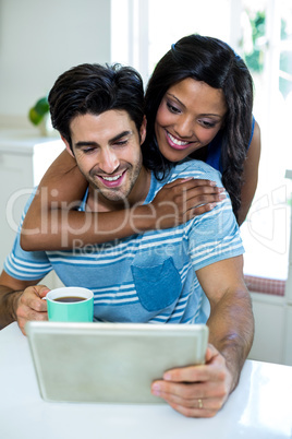 Young couple embracing while using digital tablet