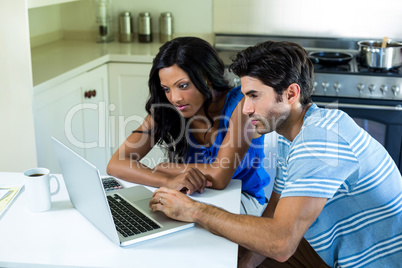 Young couple using laptop in kitchen